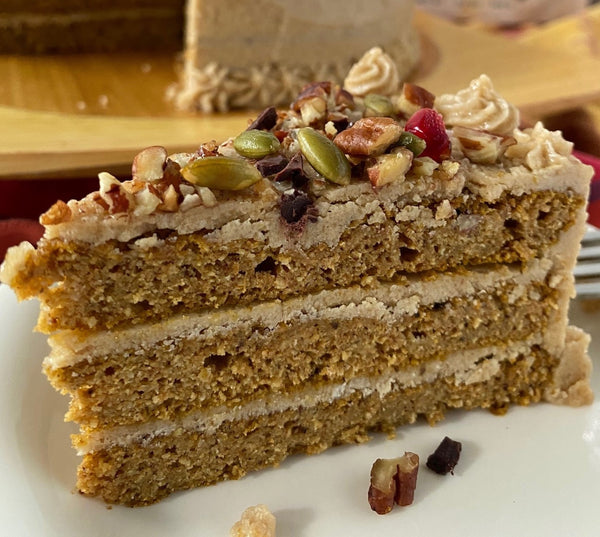 Spiced pumpkin cake layered with vegan maple butter cream, topped with toasted pecans, pumpkin seeds, chopped chocolate, and pomegranate seeds.