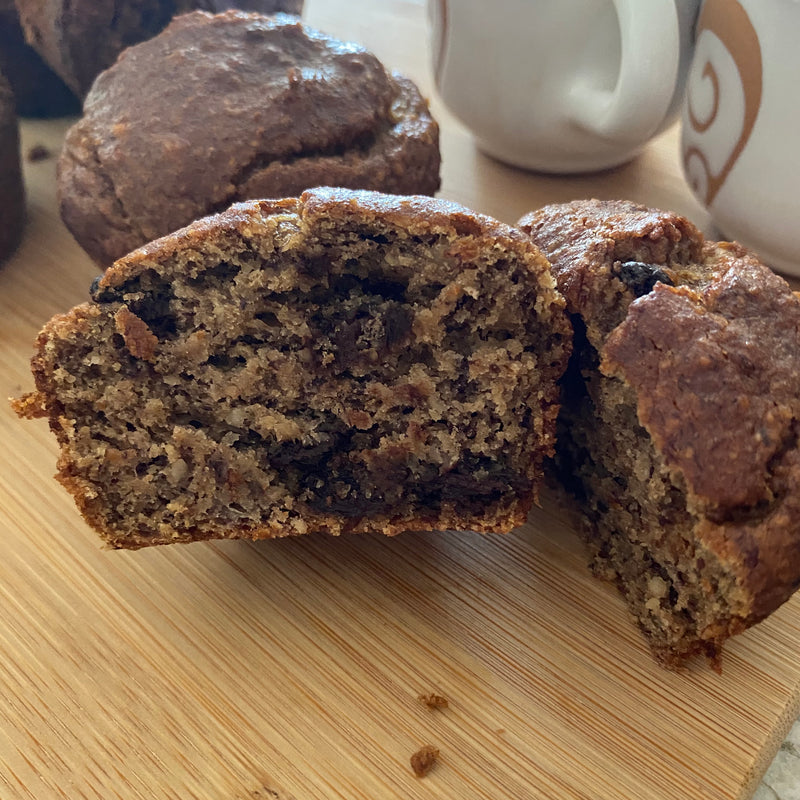 Moist and tasty banana chocolate chip muffin cut in half revealing melted chocolate chips and a mouth-watering crumb.